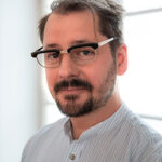 Johannes Haslinger Ein Mann mit schwarzer Briller blickt freundlich.