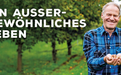 Verdammt harte Nüsse Ein lächelnder Mann im blau-schwarz-karierten Hemd hält einige Haselnüsse in seiner Hand